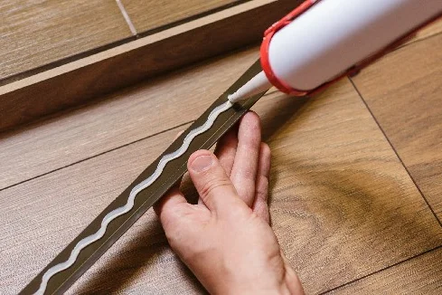 Person trägt Dichtmittel mit Kartuschenpistole auf